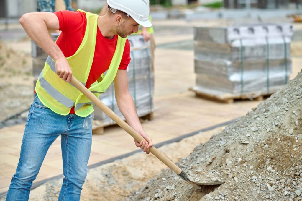 man with shovel picking up rubble construction site