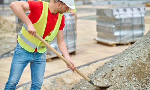 man with shovel picking up rubble construction site